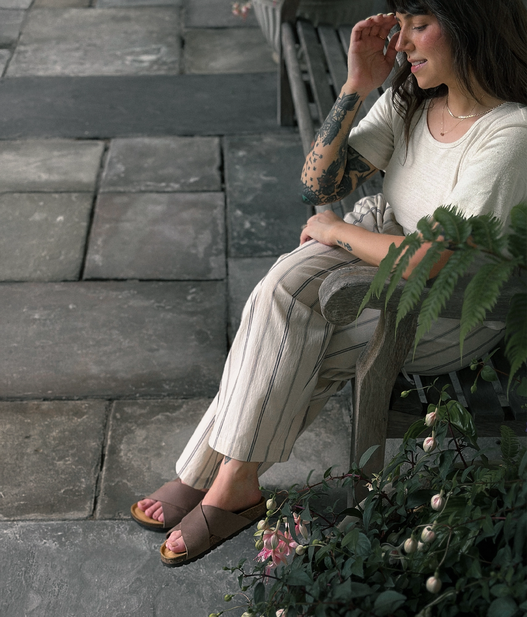 Woman wearing criss cross cork sandals in walnut brown oiled full-grain nubuck leather with a brown EVA outersole and suede footbed